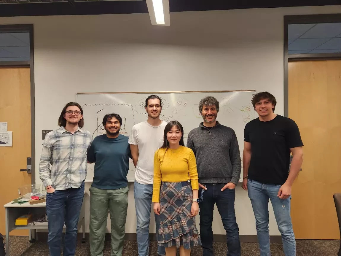 Simone with a group of students in front of a whiteboard.